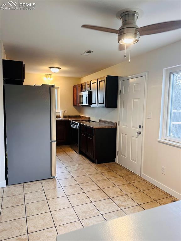 kitchen with stainless steel appliances, light tile patterned floors, dark brown cabinetry, and ceiling fan
