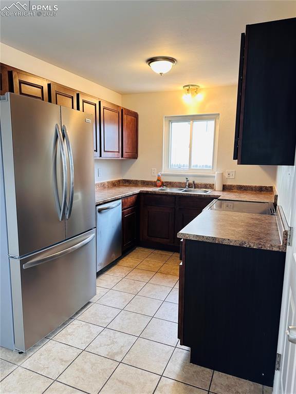 kitchen with light tile patterned flooring, appliances with stainless steel finishes, and sink
