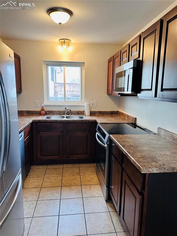 kitchen featuring dark brown cabinetry, appliances with stainless steel finishes, sink, and light tile patterned floors