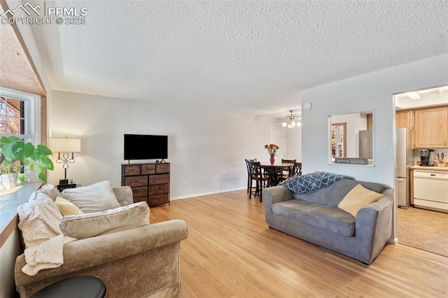 living area featuring a textured ceiling, light wood-type flooring, and baseboards