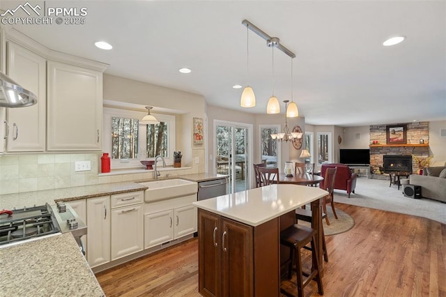 kitchen with appliances with stainless steel finishes, sink, pendant lighting, white cabinets, and a breakfast bar area