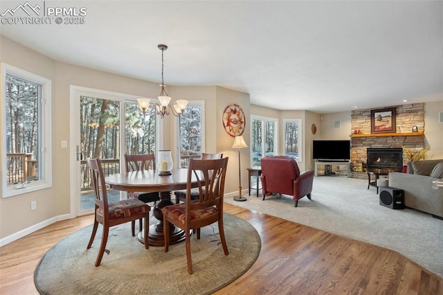 dining space featuring a fireplace, light hardwood / wood-style floors, and a notable chandelier