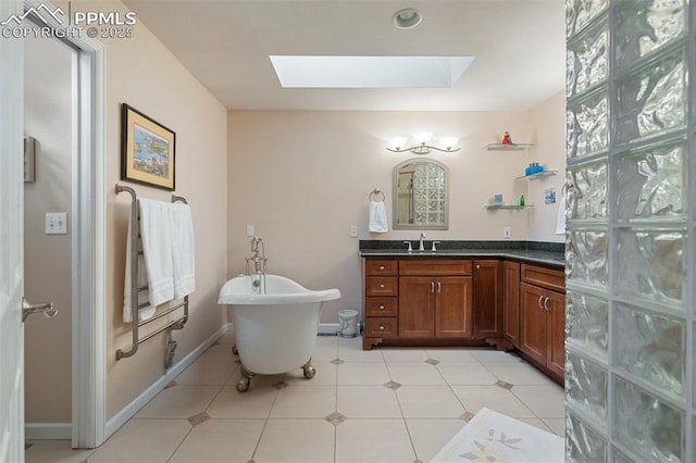 bathroom featuring tile patterned flooring, a skylight, vanity, and a bathing tub