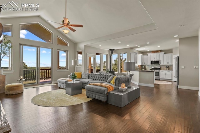 living room with ceiling fan, high vaulted ceiling, dark wood-type flooring, and a healthy amount of sunlight