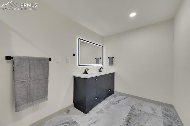 bathroom with double vanity, marble finish floor, baseboards, and a sink
