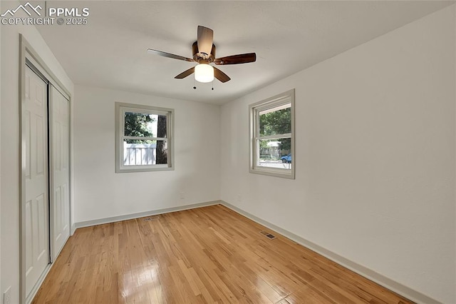 unfurnished bedroom featuring light wood finished floors, multiple windows, a closet, and visible vents