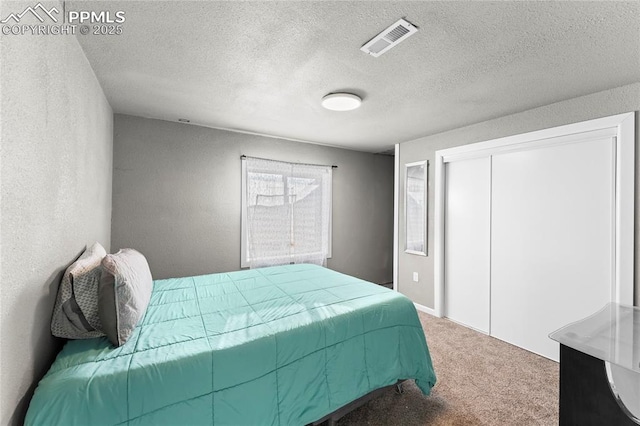 carpeted bedroom with a textured ceiling and a closet