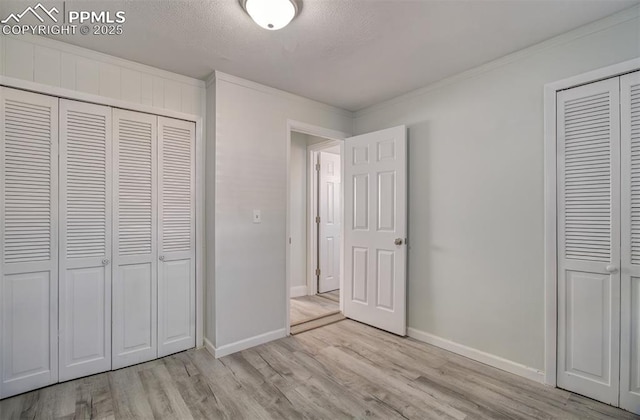 unfurnished bedroom with light wood-type flooring, ornamental molding, a textured ceiling, and a closet