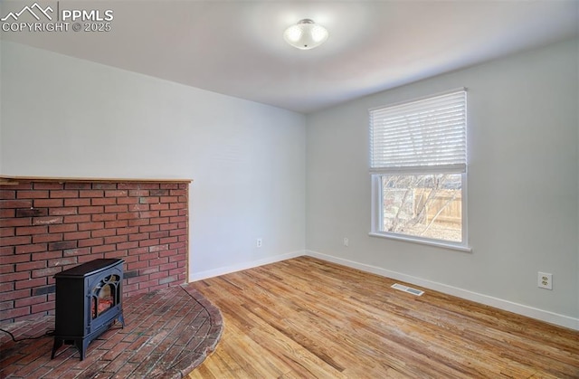 unfurnished living room featuring a wood stove and wood-type flooring