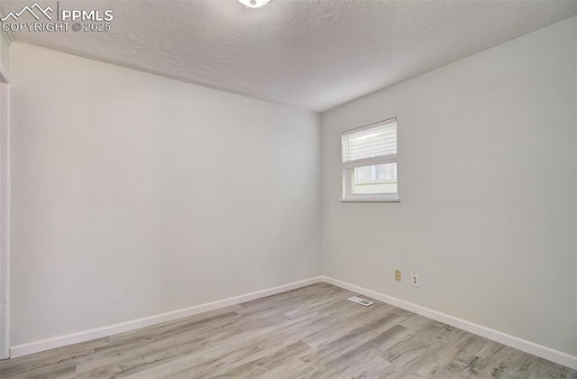 empty room with light hardwood / wood-style flooring and a textured ceiling