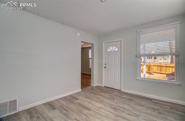 entryway with light hardwood / wood-style floors and a textured ceiling