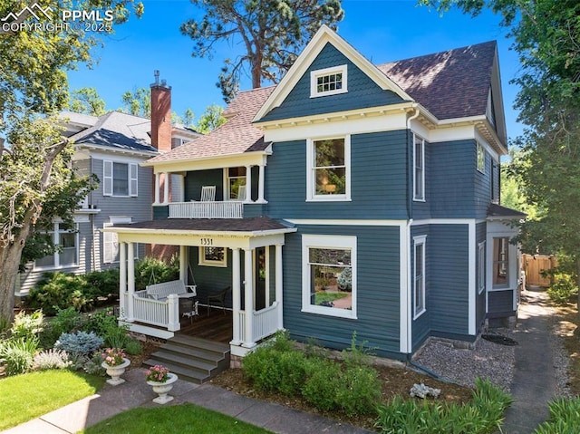 view of front of property featuring a shingled roof, covered porch, and a balcony