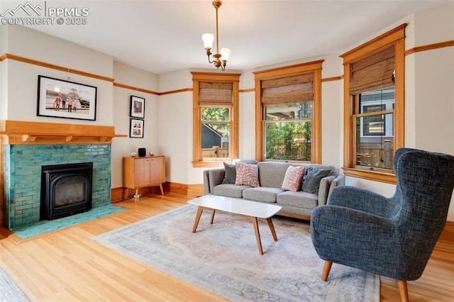 living area featuring a fireplace with flush hearth, an inviting chandelier, baseboards, and wood finished floors