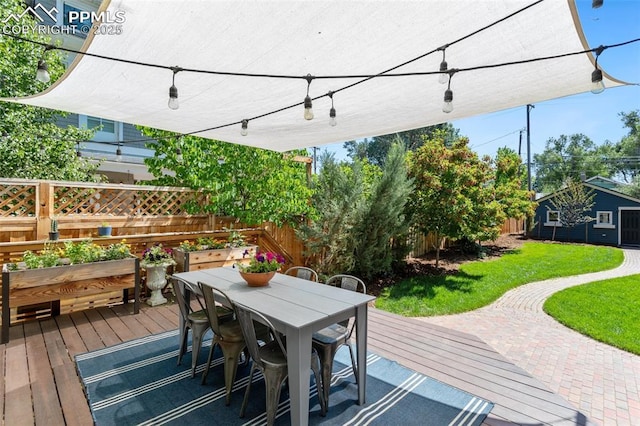 wooden deck with outdoor dining space, a lawn, a fenced backyard, and a garden