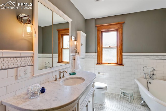 bathroom with tile patterned flooring, toilet, a wainscoted wall, vanity, and a soaking tub