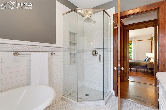 ensuite bathroom featuring a shower stall, a washtub, and connected bathroom