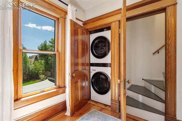 laundry room with laundry area, stacked washer / dryer, and wood finished floors