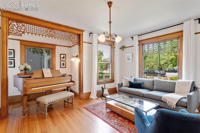 living room with baseboards, a healthy amount of sunlight, a notable chandelier, and light wood finished floors