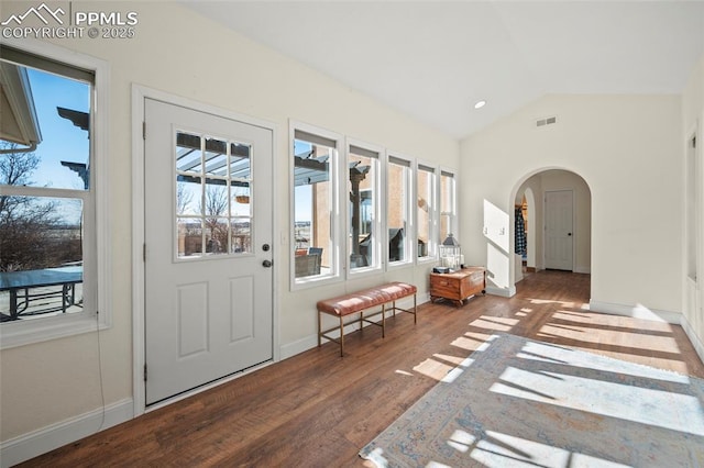 interior space featuring baseboards, visible vents, arched walkways, lofted ceiling, and wood finished floors