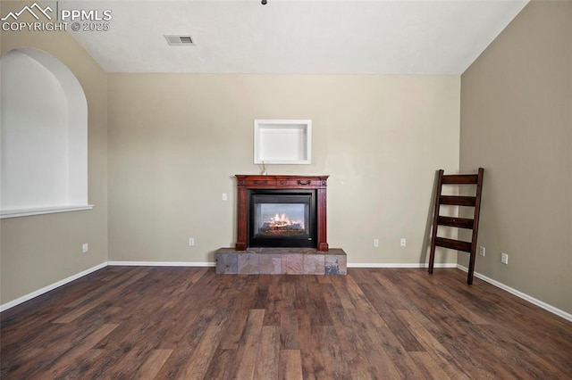 unfurnished living room with baseboards, visible vents, a tiled fireplace, and wood finished floors