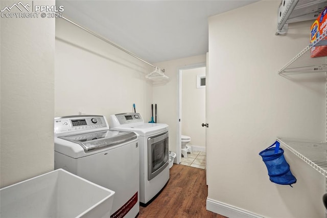 laundry room with laundry area, dark wood-type flooring, a sink, baseboards, and washer and clothes dryer