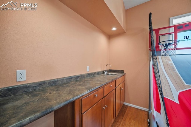 interior space with baseboards, brown cabinetry, dark countertops, light wood-style floors, and a sink