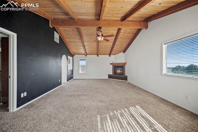 unfurnished living room featuring lofted ceiling with beams, ceiling fan, wooden ceiling, carpet flooring, and a glass covered fireplace