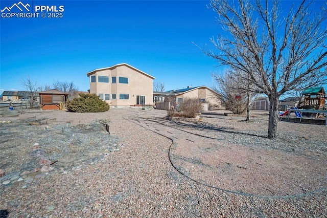 view of front of property with stucco siding, an outdoor structure, and a shed