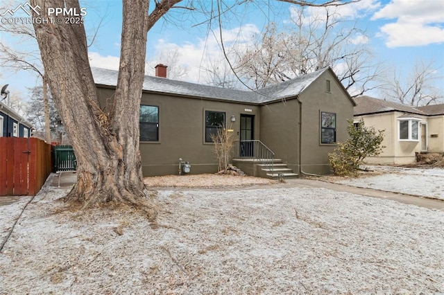 view of front of property with stucco siding, fence, central AC, and a chimney