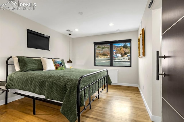 bedroom with recessed lighting, wood finished floors, visible vents, baseboards, and radiator