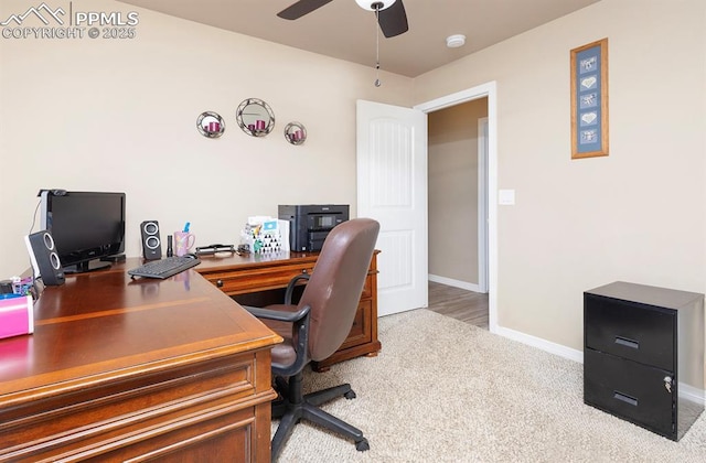 carpeted office space with a ceiling fan and baseboards