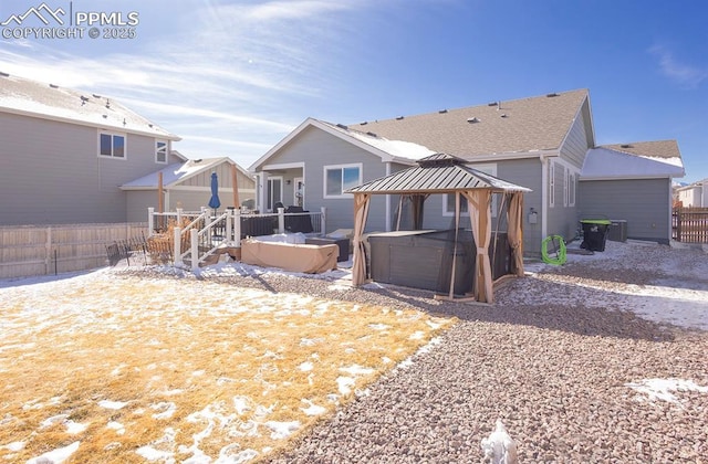 snow covered house featuring a deck, a gazebo, fence, and a hot tub