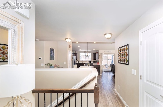 corridor featuring recessed lighting, baseboards, an upstairs landing, and wood finished floors