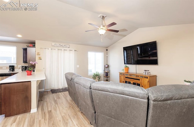 living room featuring lofted ceiling, ceiling fan, and light wood-style flooring