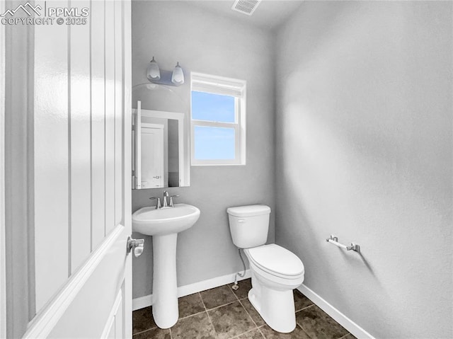 bathroom featuring tile patterned flooring, toilet, a sink, visible vents, and baseboards