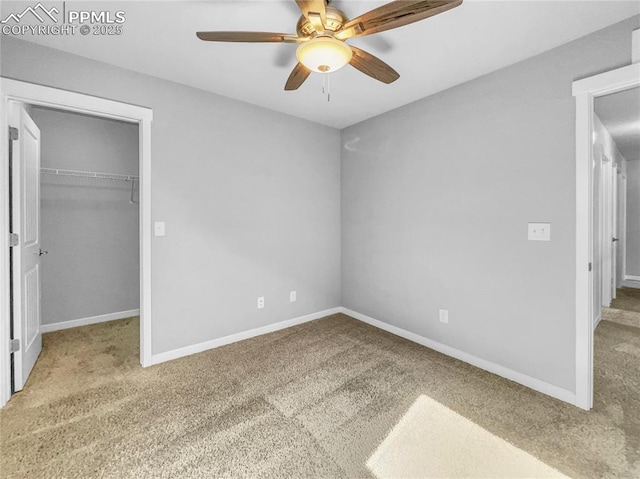 unfurnished bedroom with ceiling fan, light carpet, baseboards, a closet, and a walk in closet