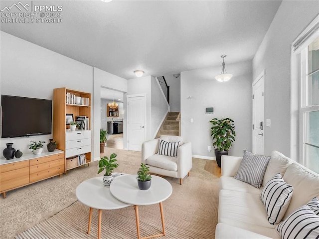 carpeted living room with baseboards and stairs