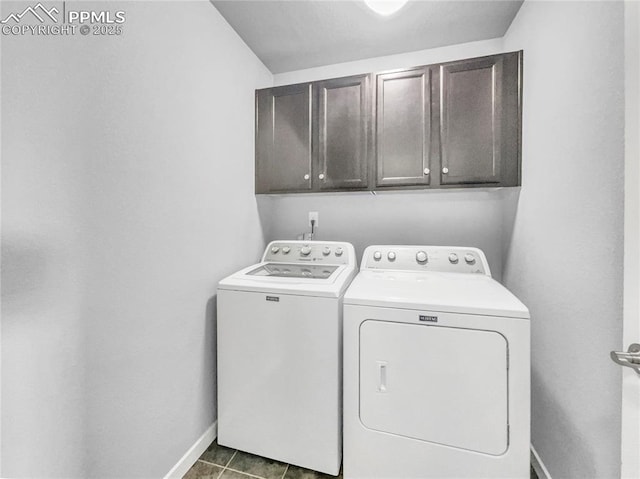 laundry room featuring cabinet space, baseboards, separate washer and dryer, and dark tile patterned flooring