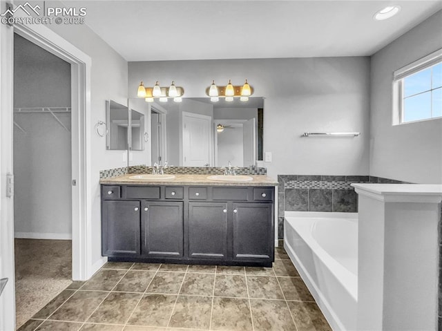 full bath featuring double vanity, a garden tub, a spacious closet, and a sink