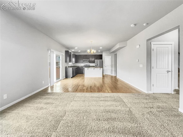 kitchen with light wood-style flooring, a notable chandelier, open floor plan, appliances with stainless steel finishes, and a center island