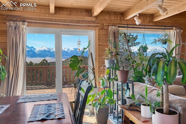 interior space featuring wooden walls, beamed ceiling, wood ceiling, and a mountain view