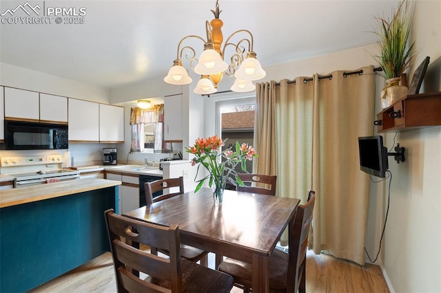 kitchen with light hardwood / wood-style flooring, white cabinets, black appliances, pendant lighting, and an inviting chandelier