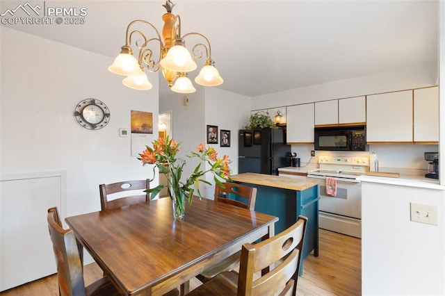 kitchen featuring light hardwood / wood-style floors, butcher block countertops, black appliances, white cabinets, and hanging light fixtures