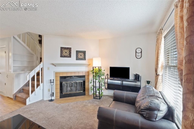 living room featuring a textured ceiling, a tiled fireplace, and light colored carpet