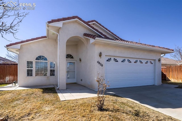 view of front facade featuring stucco siding, concrete driveway, fence, a garage, and a tiled roof