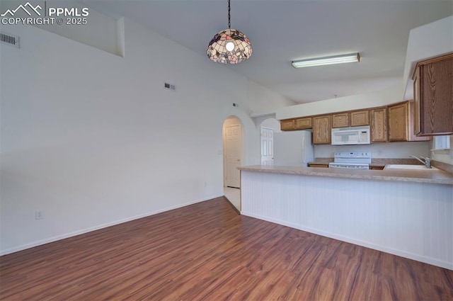 kitchen featuring arched walkways, dark wood-style flooring, brown cabinetry, a sink, and white appliances