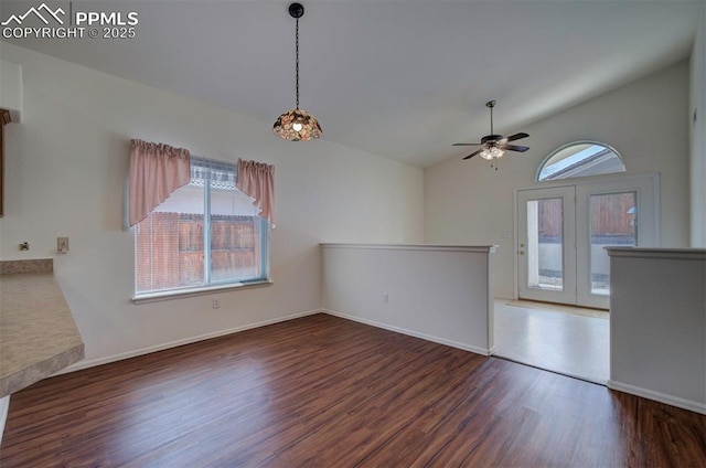 interior space with ceiling fan, a wealth of natural light, vaulted ceiling, and wood finished floors