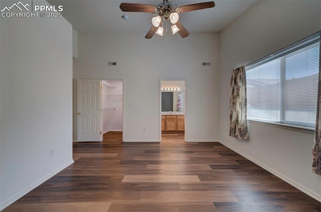 unfurnished bedroom with baseboards, a spacious closet, visible vents, and wood finished floors