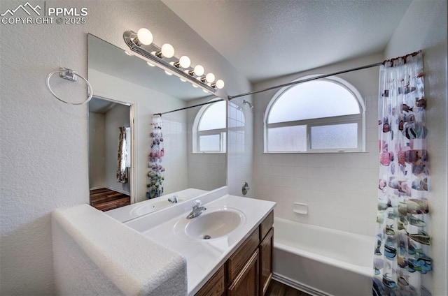 bathroom with a textured wall, shower / tub combo with curtain, a textured ceiling, and vanity