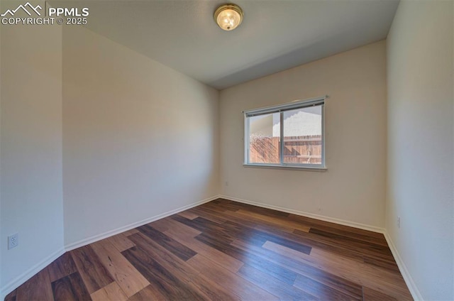 empty room with dark wood-style flooring and baseboards